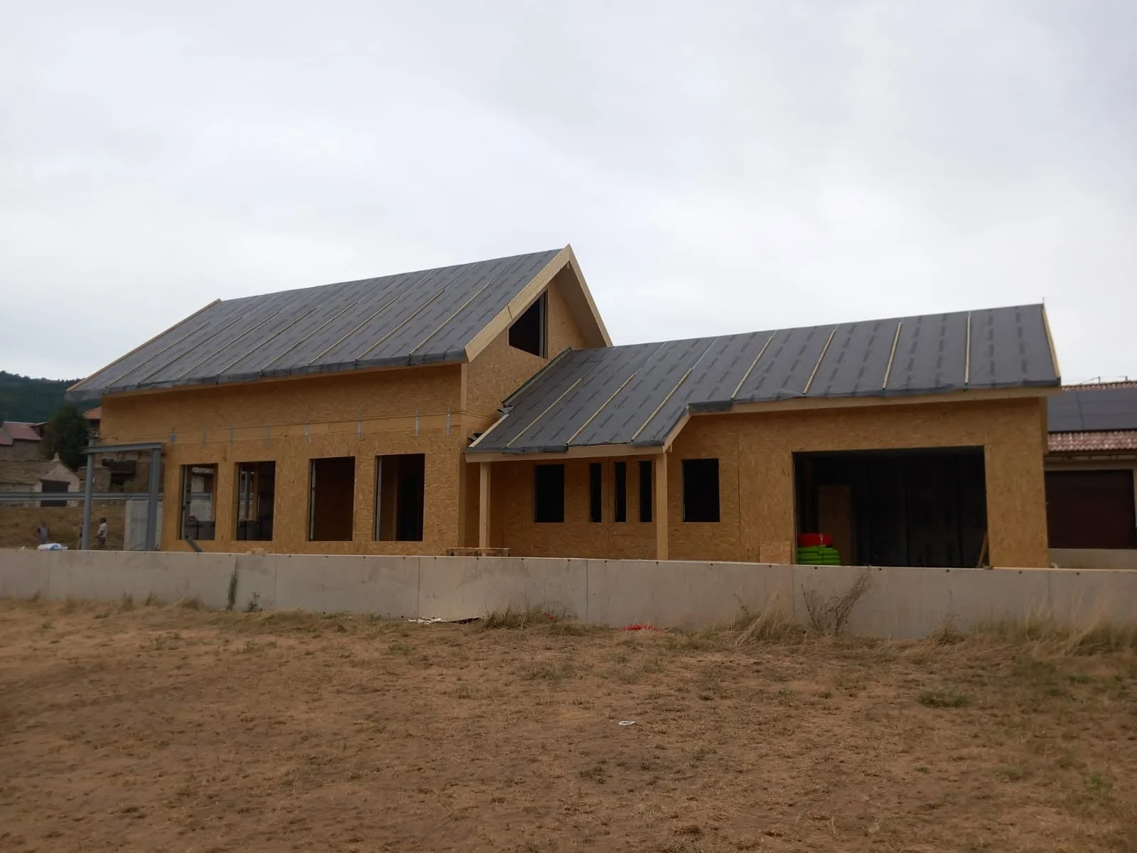 Rear elevation showing the larger Aratorés house with connected volume during progress