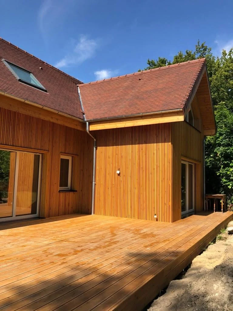 Corner view of the residence showing deck, larch cladding and roof geometry