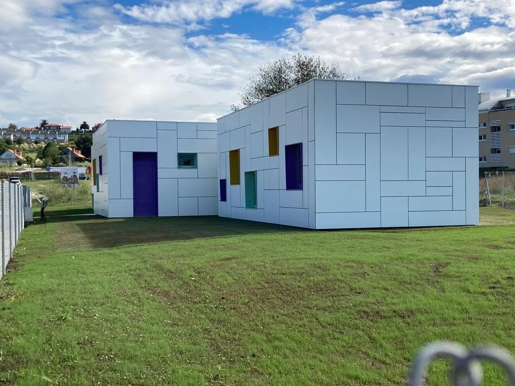 Completed Galicia modular public kindergarten with white geometric façade and coloured windows