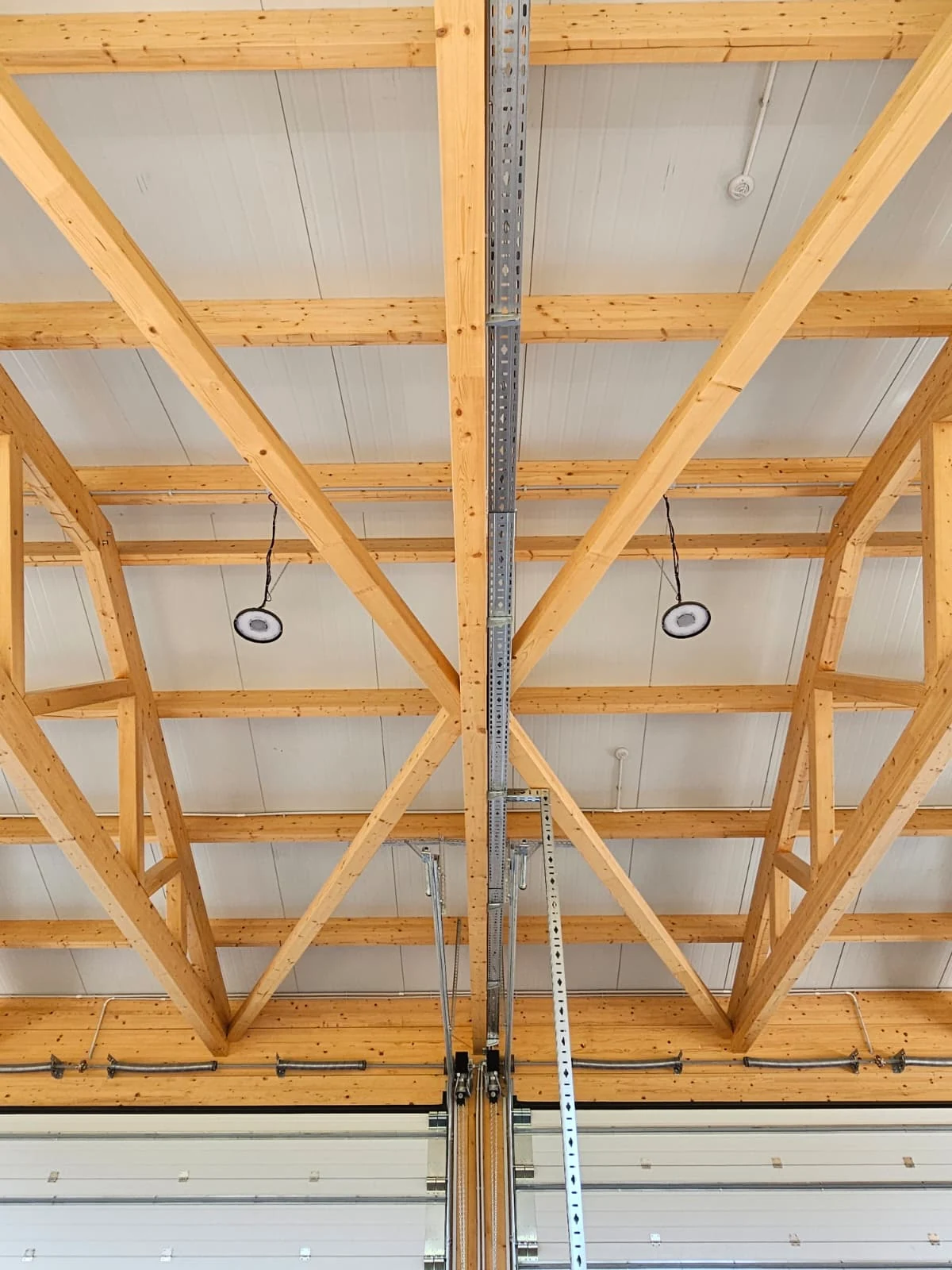 Symmetrical roof bracing and timber structural grid above the industrial hall doors