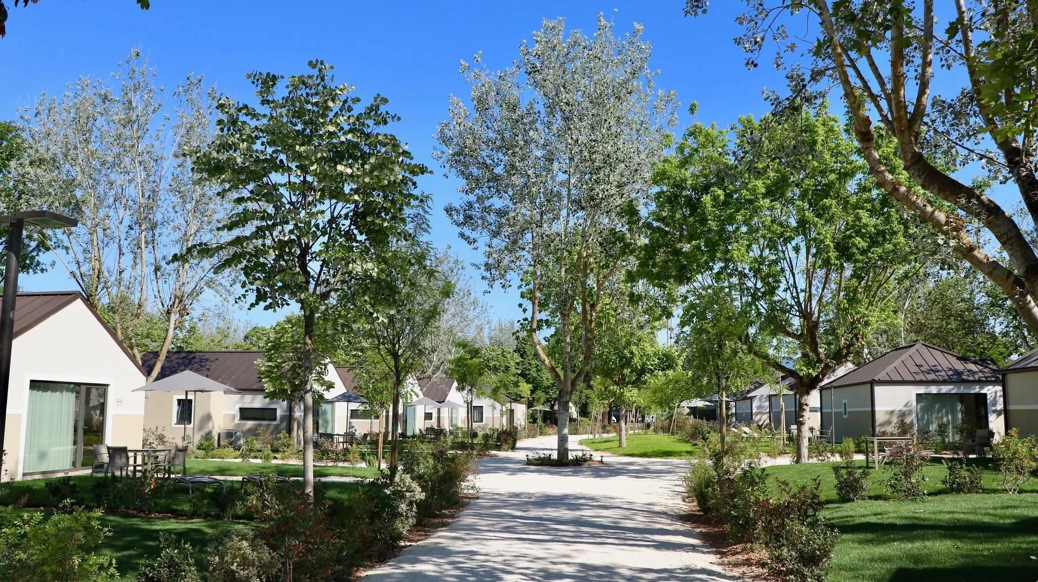 Landscaped central path between repeated tourist accommodation units in Italy