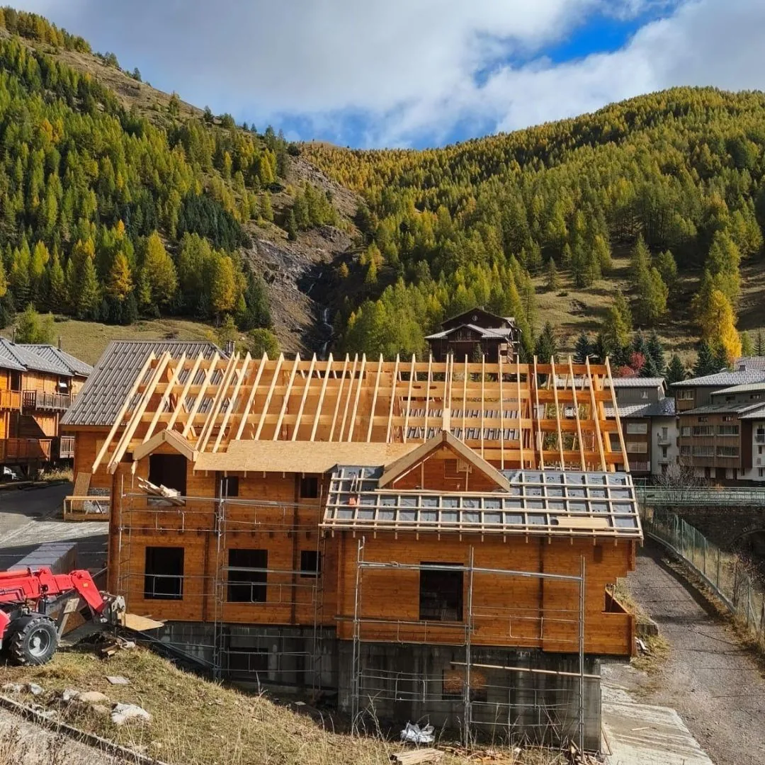 Log house timber structure under construction in an Alpine setting