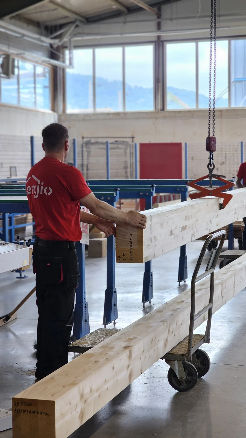 ERGIO production worker handling a prefabricated structural timber member inside the factory