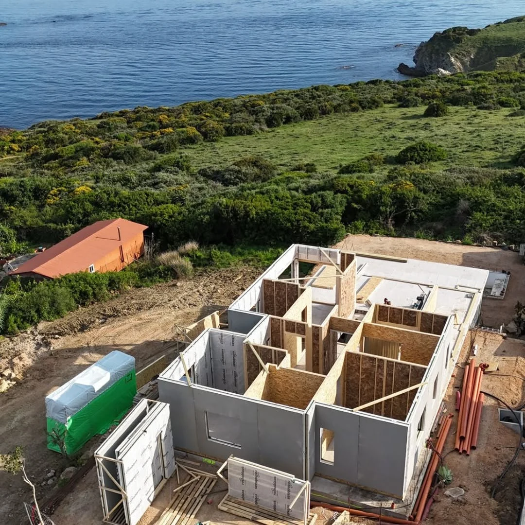 Timber frame building being assembled on a coastal construction site